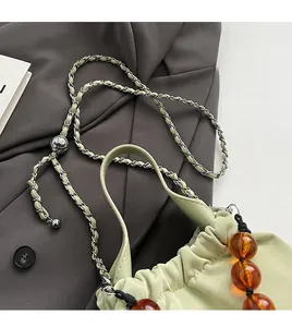 Detail of light green PU crossbody bag featuring amber acrylic beads and chain strap