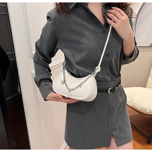 Sac demi-lune blanc avec chaîne à cœur et perles porté par un mannequin
