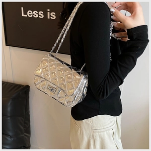 Detail of silver quilted texture with metallic twist lock and chain strap on shoulder bag