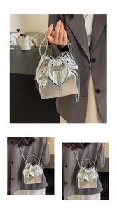 Detail of silver metallic bucket bag with ring handle and delicate chain strap