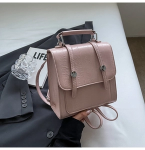 Close-up of small pink backpack with vertical stripe texture and dual magnetic buckles