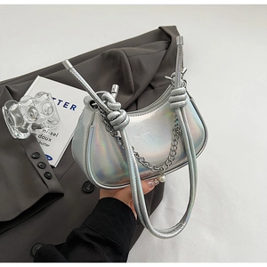 Close-up of holographic silver shoulder bag with metallic chain and knotted handle detail