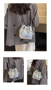 Detail of silver holographic bucket bag with metal ring handle and chain strap
