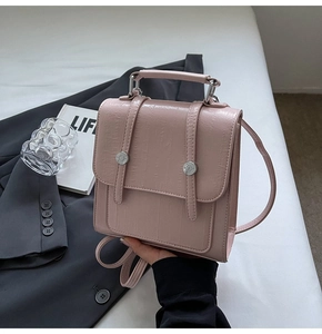 Detail of pink faux leather crossbody bag with vertical straps and silver hardware