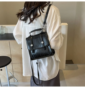Close-up of black glossy backpack with silver buckle on a female model