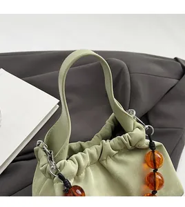 Detail of light green ruched leather handbag with amber beads and silver metal hardware