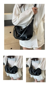 Detail of slouchy black crocodile texture faux leather tote bag on model indoors