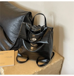Detail of black wrinkled leather backpack with silver metal turn-lock on stone display