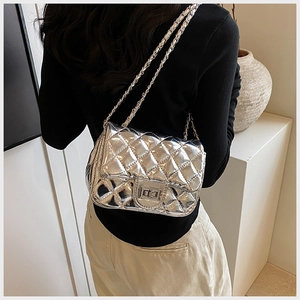 Macro detail of silver quilted pattern on crossbody bag with metal chain strap