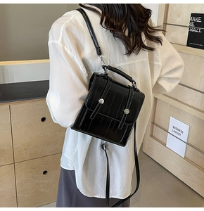 Close-up of black textured mini backpack featuring vertical stripes and silver metal clasp
