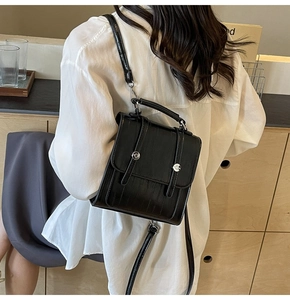 Detail of a black crocodile pattern backpack with silver hardware on a casual model