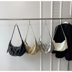 Four crescent tote bags in black, gold, silver and beige hanging on a wall