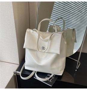 Detail of white crocodile embossed leather backpack with a silver metal twist-lock closure