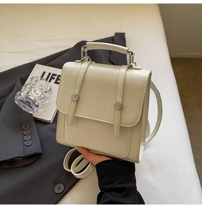 Detail of minimalist cream faux crocodile embossed handbag with silver metal lock closure