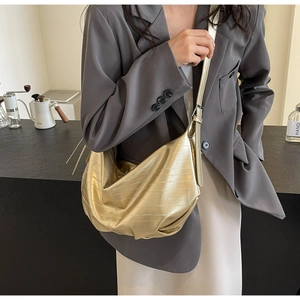 Detail of metallic gold pleated tote bag with adjustable strap worn on model