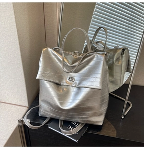 Detail of silver metallic backpack featuring horizontal pleats and a polished turn-lock