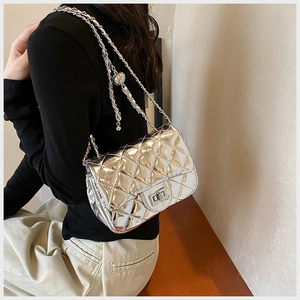 Detail of silver quilted crossbody bag showing metal chain strap and turn-lock closure