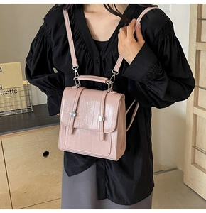 Detail of pink faux crocodile leather texture and metallic buckles on a stylish backpack