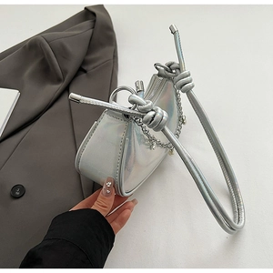 Close-up of silver laser texture underarm bag with knot strap and chain decoration