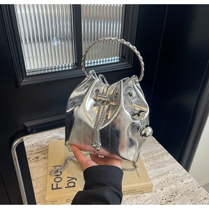 Detail of silver metallic bucket bag featuring drawstring closure and chain strap