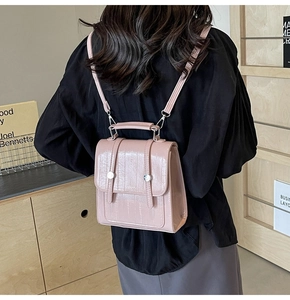 Detail view of glossy pale pink backpack showing faux leather texture and silver buttons