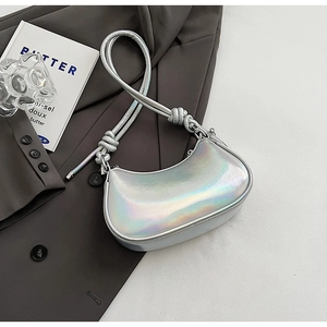 Top view of a silver holographic half-moon bag with knot strap detail on a dark blazer
