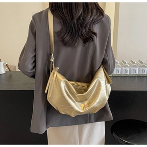 Detailed shot of golden crescent crossbody bag with embossed texture and adjustable strap
