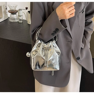 Detail of silver metallic bucket bag with chain drawstring and spherical pendant
