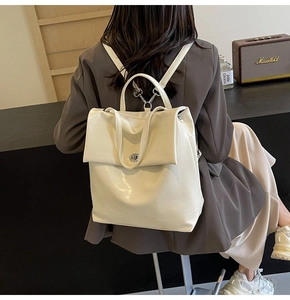 Detailed view of cream crocodile textured leather backpack with silver twist lock and handle