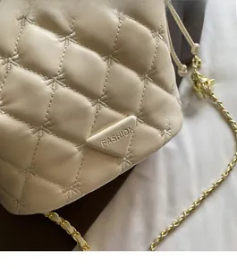 Détail d'un sac seau matelassé beige montrant la texture du cuir et le logo triangle