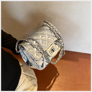 Detail of silver quilted crossbody bag with metallic finish and woven chain strap
