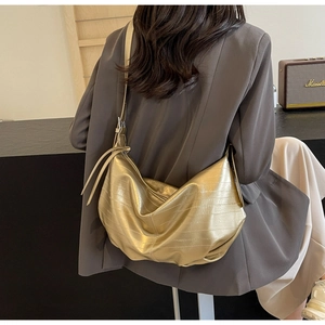 Detail of metallic gold tote bag with pleated leather texture shown on model shoulder