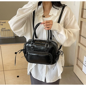 Detail of glossy black crinkled leather bag with silver metal zipper and D-ring hardware