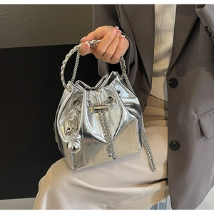 Detail of silver metallic bucket bag with ring handle and chic charms on gray suit