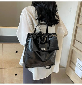 Detail of the glossy black crocodile pattern backpack with metallic turn-lock closure