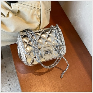 Detailed macro view of silver quilted crossbody bag with metal twist lock and chain strap