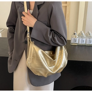 Detail of a gold metallic hobo bag with pleated texture and adjustable shoulder strap