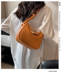 Vue arrière du mannequin portant un sac seau Lindy en cuir orange grainé de litchi