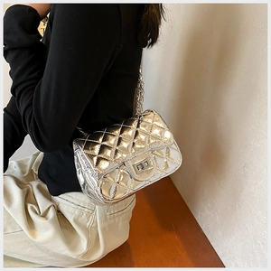 Detail of silver quilted chain bag with metallic finish and square turn-lock closure