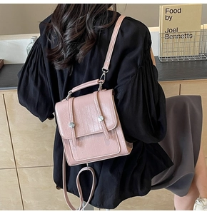 Detailed view of pink textured vertical crossbody bag with silver hardware and shoulder strap