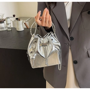 Close-up of silver metallic bucket bag featuring round metal handles and chain strap