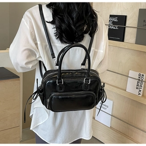 Detail of a black shiny faux leather convertible backpack and handbag with silver zippers