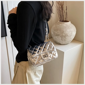 Detail of silver metallic quilted crossbody bag with a square rotary metal lock