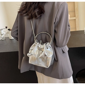 Close-up of silver metallic bucket bag with fringe tassels and chain strap detail