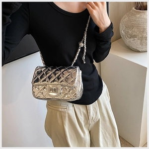 Detail of silver quilted crossbody bag featuring metal turn lock and chain strap