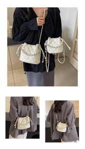 Détail de sacs seaux matelassés blancs avec chaîne de perles et bandoulières métal