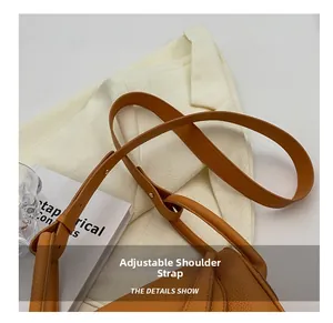 Détail de la bandoulière réglable avec boucle en métal sur un sac seau marron grainé