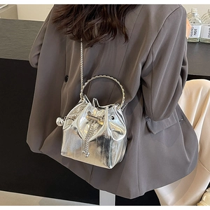 Detail of silver bucket bag with metallic ring handle, chain strap and tassel drawstring