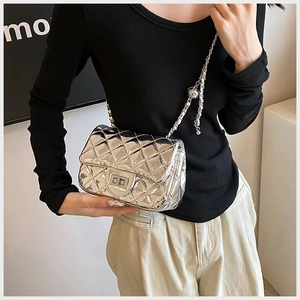 Detail of silver quilted chain bag with metallic finish and metal twist lock on model