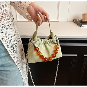 Detail of light green suede bucket bag featuring large amber beads and silver chain